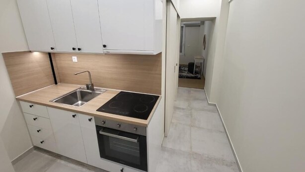 Cocina compacta con fregadero, estufa, horno y armarios blancos.