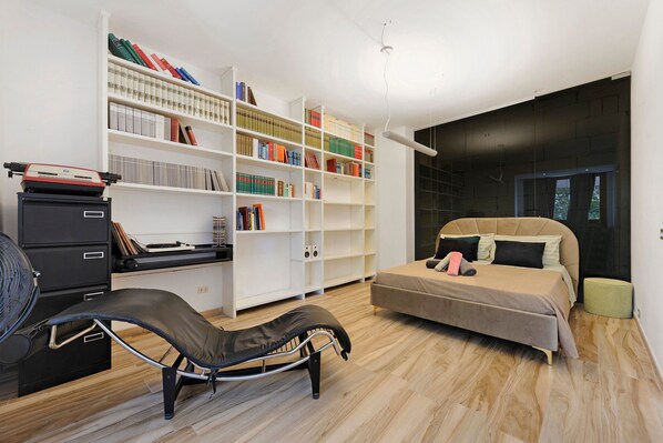 Une chambre à coucher moderne comprenant un lit, une table de chevet, une bibliothèque et un bureau avec une chaise.