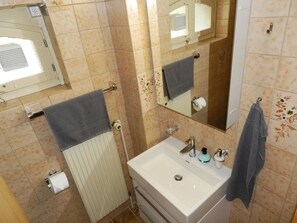 A bathroom with a white sink, a mirror, a towel rack, and a toilet. - Studio Oehrli Studio, Dusche oder Bad, WC 2-Bettwohnung by Interhome (Gstaad)
