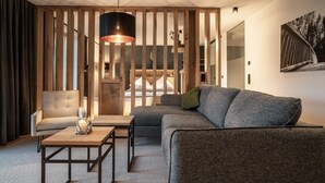 A modern living room with a sectional sofa, a small table, a chair, and a hanging light fixture.