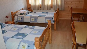 Een kamer met twee bedden, een houten tafel en een stoel.