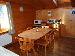 Ein Holzinterieur mit Esstisch und Stühlen, einer Mikrowelle und einer Kaffeemaschine auf einem Holzschrank.