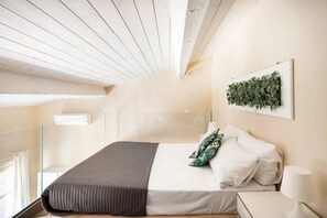 A bedroom with a bed, pillows, a bedside table, a lamp, and a wall-mounted plant. - Stylish Florence Apartment Steps from the Duomo (Firenze)