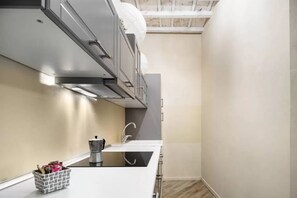 A compact kitchen with a built-in stove, a sink, and a small storage unit. - Stylish Florence Apartment Steps from the Duomo (Firenze)