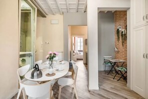 A modern kitchen with a dining area, a brick accent wall, and a view to a living area. - Stylish Florence Apartment Steps from the Duomo (Firenze)