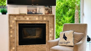 A living room with a fireplace, a television, and a chair with a pillow.
