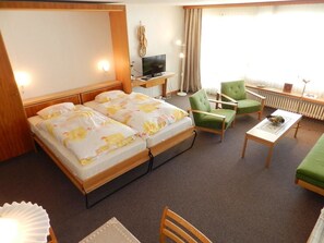 Une chambre d’hôtel avec deux lits, une télévision, un bureau et une chaise.