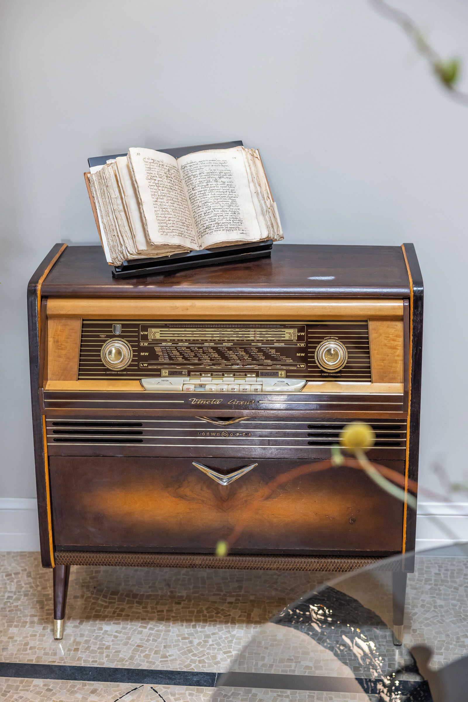A vintage radio on a wooden cabinet with a book on top.