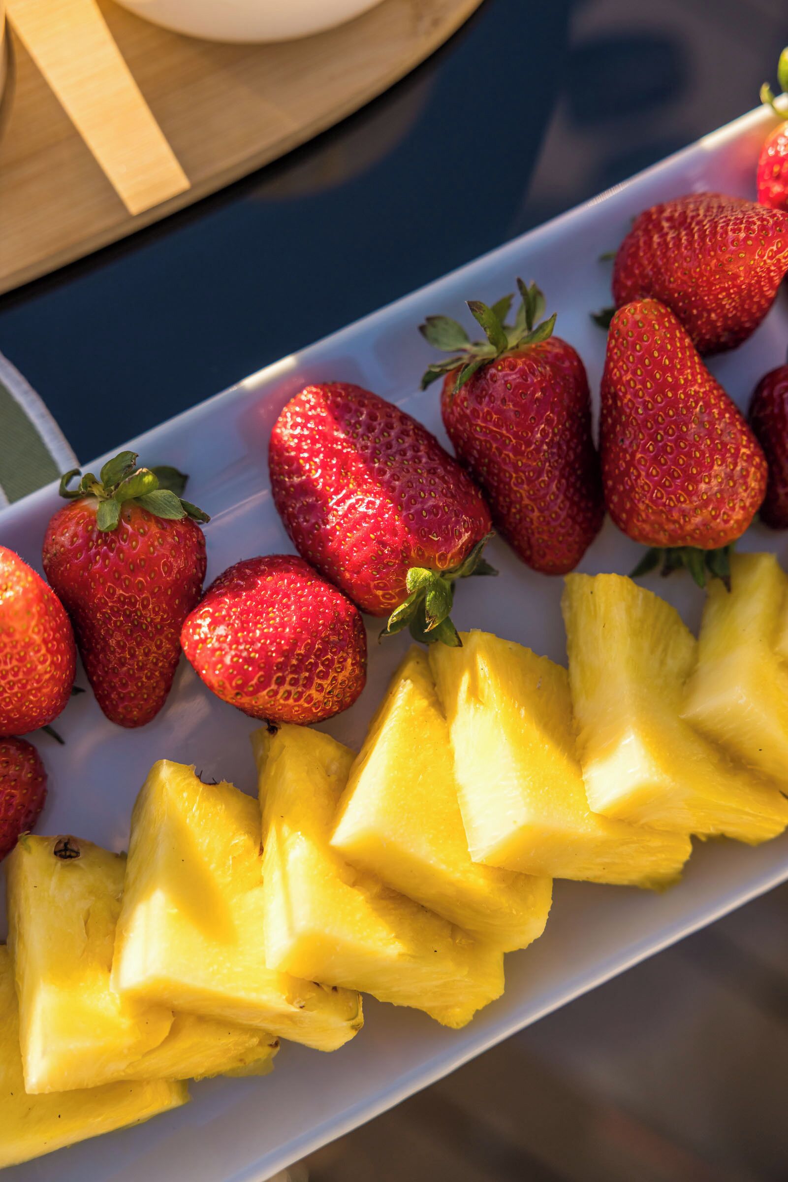 Un plato con piña en rodajas y fresas.
