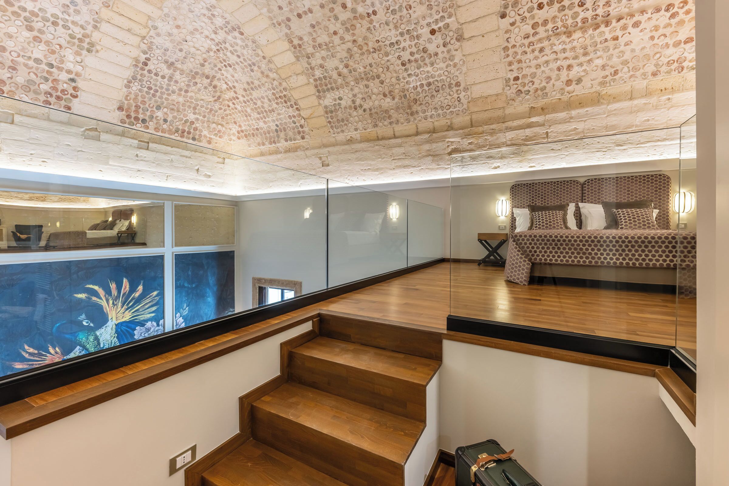 Un interior modern amb una escala, un llit amb roba de llit estampada i un sostre decoratiu.