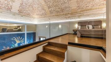 Un interior modern amb una escala, un llit amb roba de llit estampada i un sostre decoratiu.