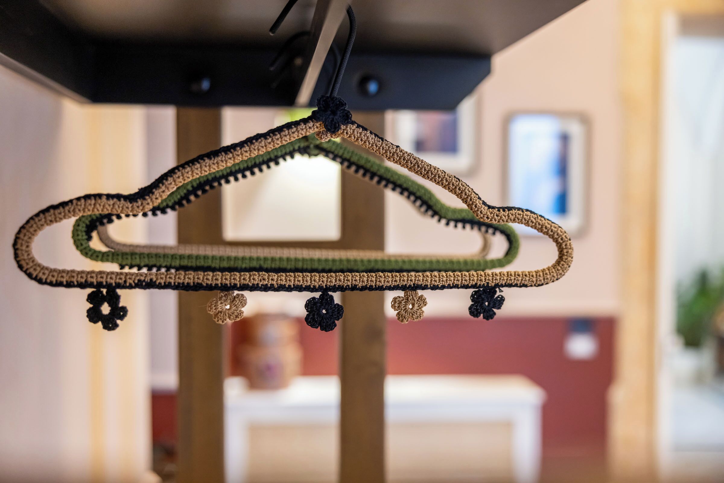 A crochet hanger with a tassel and decorative elements, hanging from a ceiling fixture.