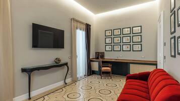 A living room with a red sofa, a TV mounted on the wall, a console table, and framed artwork on the wall.