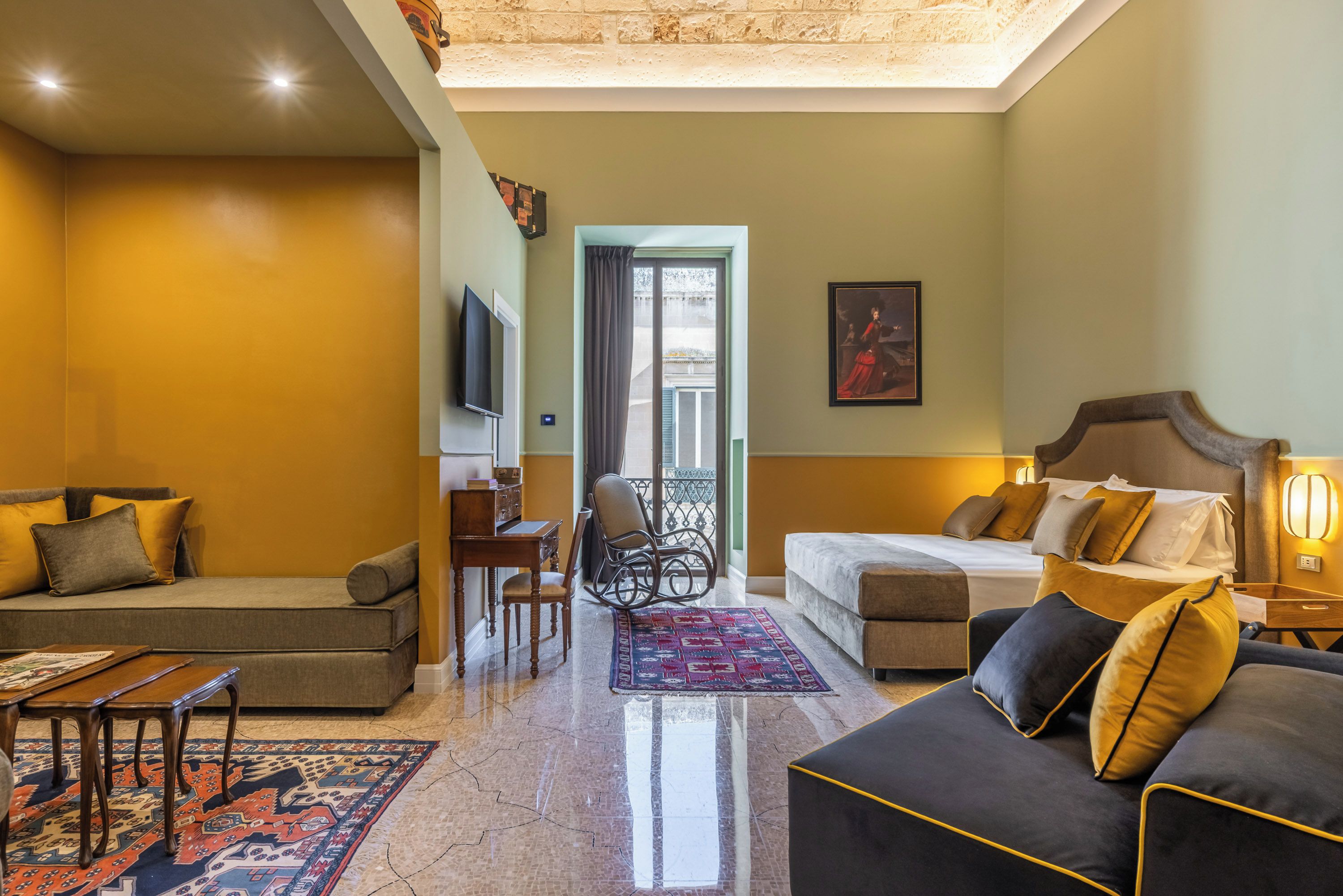 Ein Hotelzimmer mit Sofa, Bett, Schreibtisch und Stuhl.