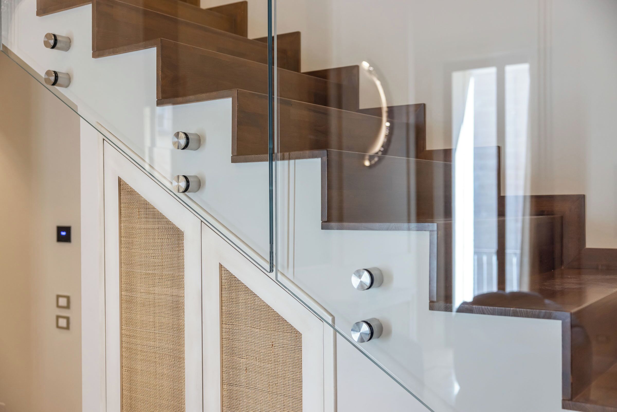 Una escalera moderna con barandillas de vidrio y escalones de madera.