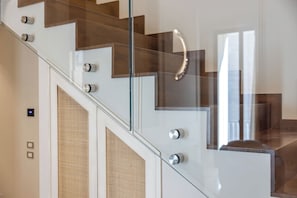 A modern staircase with glass railings and wooden steps.