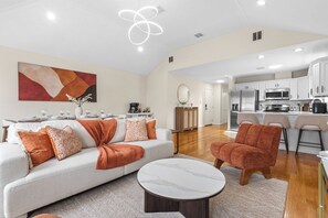 Ein modernes Wohnzimmer mit einer Couch, einem Couchtisch und einer Küche im Hintergrund.