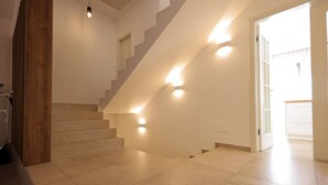Una escalera con barandilla de madera y una lámpara en la pared.
