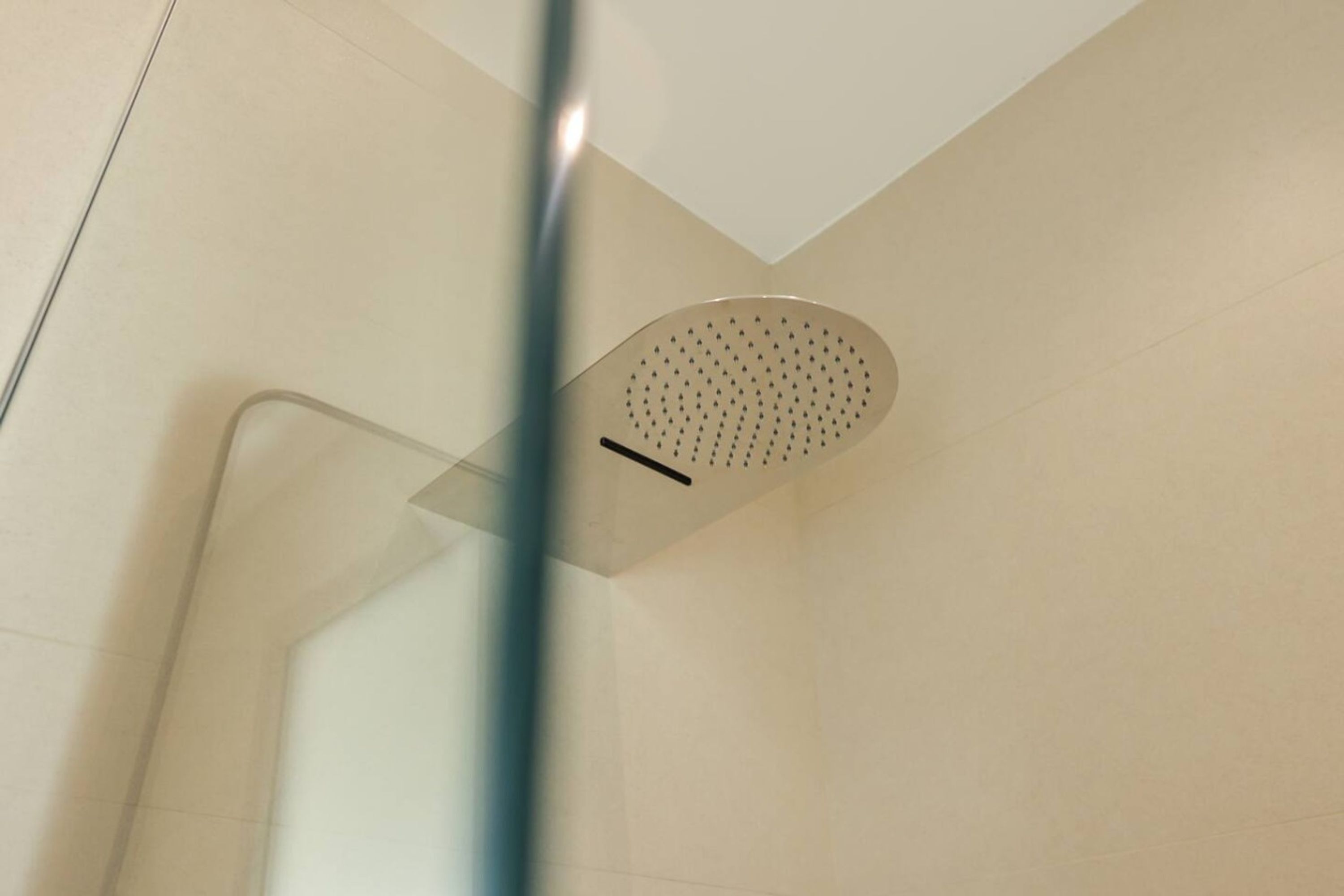 Een douchekop in een badkamer met witte betegelde wanden.
