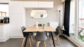 A modern dining area with a wooden table, black chairs, a white radiator, and a large window with a view.