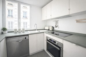 Eine moderne Küche mit Geschirrspüler, Backofen und einem Fenster mit Blick auf ein Gebäude.