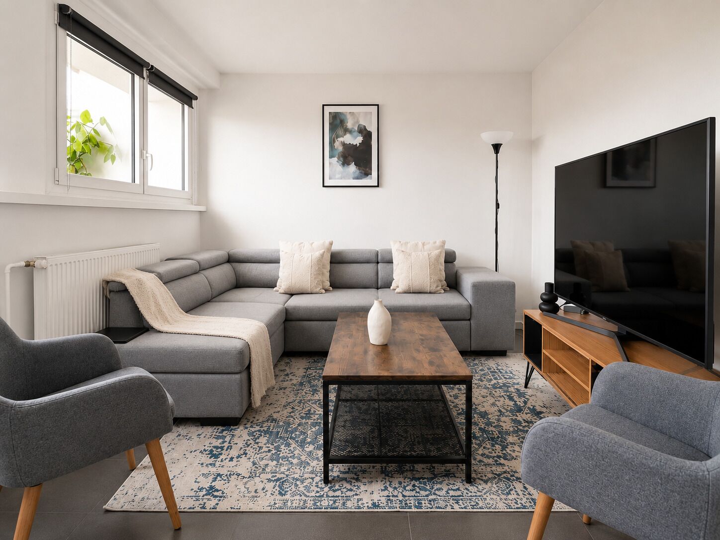 A modern living room with a sectional sofa, a coffee table, and a flat-screen TV.