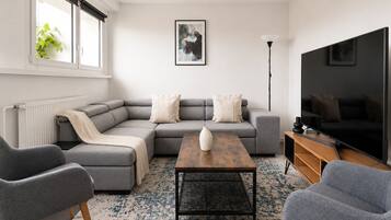 A modern living room with a sectional sofa, a coffee table, and a flat-screen TV.
