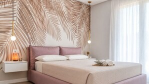 A modern bedroom with a bed, bedside lamps, and a wall with a leaf pattern. - Nala by Case al Lago (Castel Venzago)