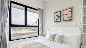 Quarto de hotel com uma cama grande, vista para uma ponte e arte abstrata nas paredes.