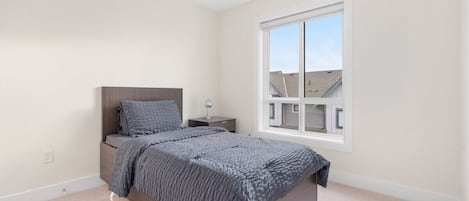 Un dormitorio con cama, mesita de noche y ventana.
