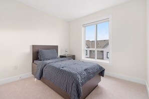 Een slaapkamer met een bed, nachtkastje en raam.
