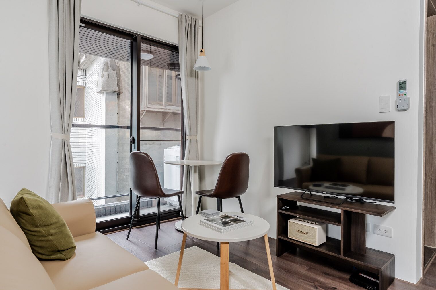 A modern living room with a sofa, two chairs, a small table, a television, and a sound system.