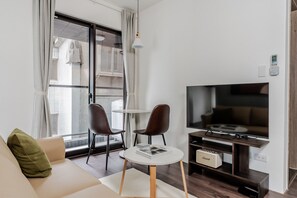 A modern living room with a sofa, two chairs, a small table, a television, and a sound system. - Blueground | Zhengshou District, balcony, nr park (TPE-1) (Taipei)