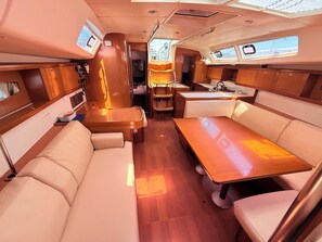 A compact, well-lit interior with a central dining table, cushioned seating, and a small kitchenette. - Sun-Kissed Sailing Adventure in Zadar, Croatia (Bibinje)