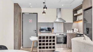A modern kitchen with a microwave, oven, and stainless steel range hood. There is a white bar stool and a built-in wine rack. - Softstay, Foreshore Cape Town CBD (Cape Town)