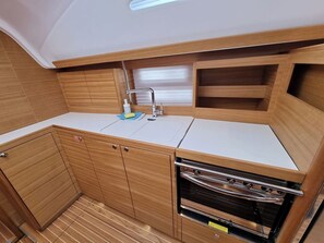 Eine kleine Küche mit Holzausstattung, einem Spülbecken und einem eingebauten Backofen.