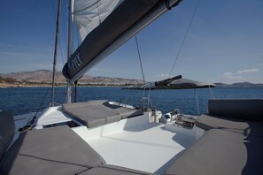 A sailboat's deck with seating, a mast, and a view of a coastal landscape. - Sun-Kissed Sailing Adventure in Islas Sarónicas (Alimos)