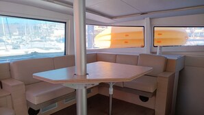 Espaço interior compacto com mesa dobrável, assentos acolchoados e amplas janelas com vista para o exterior.