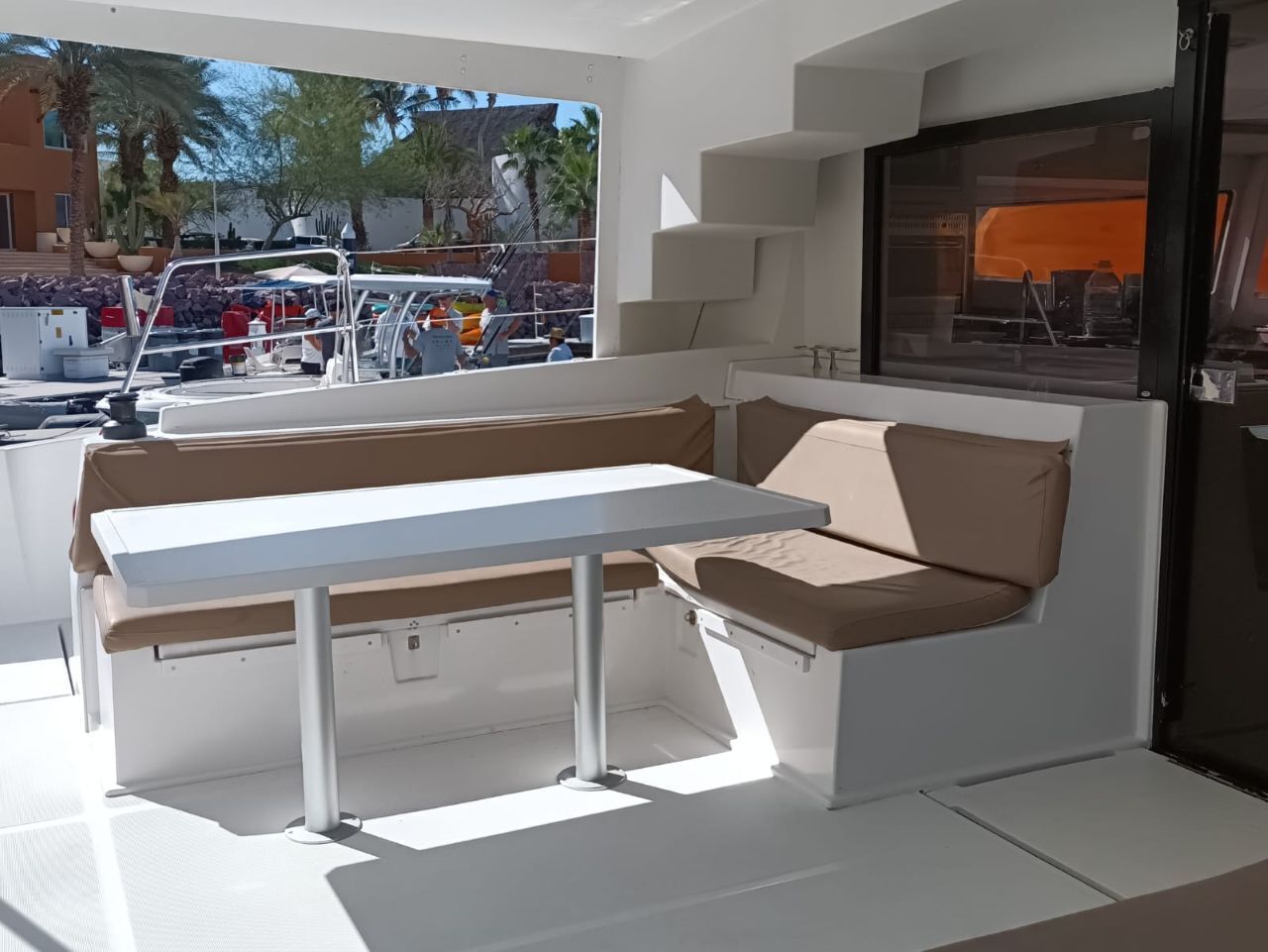 Interior de barco com mesa branca e assentos acolchoados.