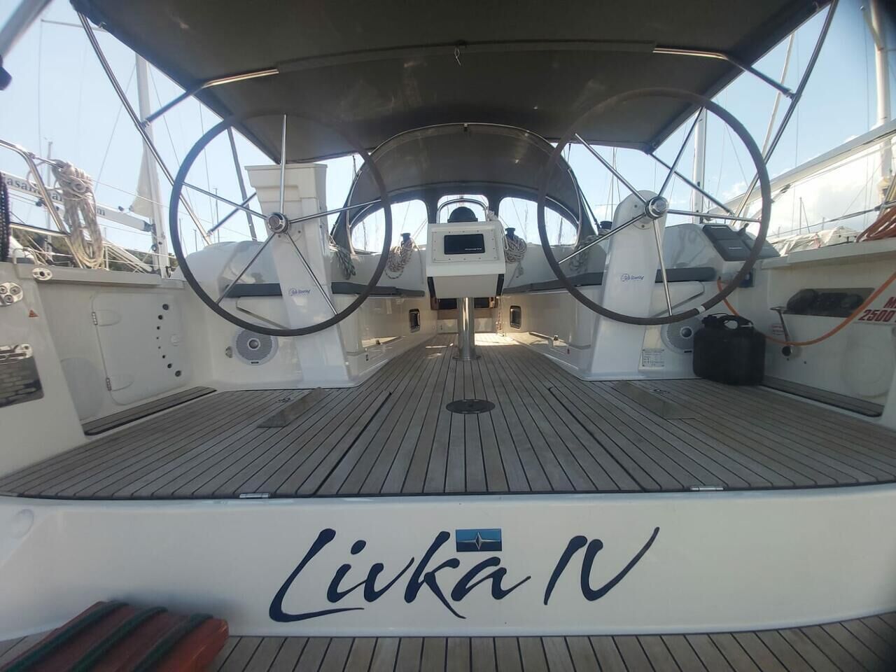 Convés de barco com um leme, painel de controle e o nome 'Lika N' na lateral.