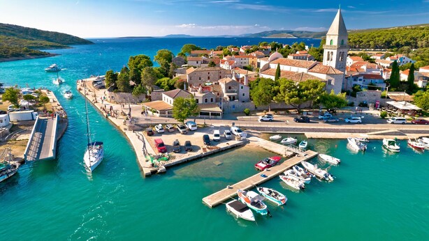 A coastal town with a marina, buildings, and a church. - Sun-Kissed Sailing Adventure in Northern Croatia (Mali Lošinj)