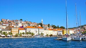A coastal town with buildings, a church, and boats docked by the water. - Sun-Kissed Sailing Adventure in Northern Croatia (Mali Lošinj)