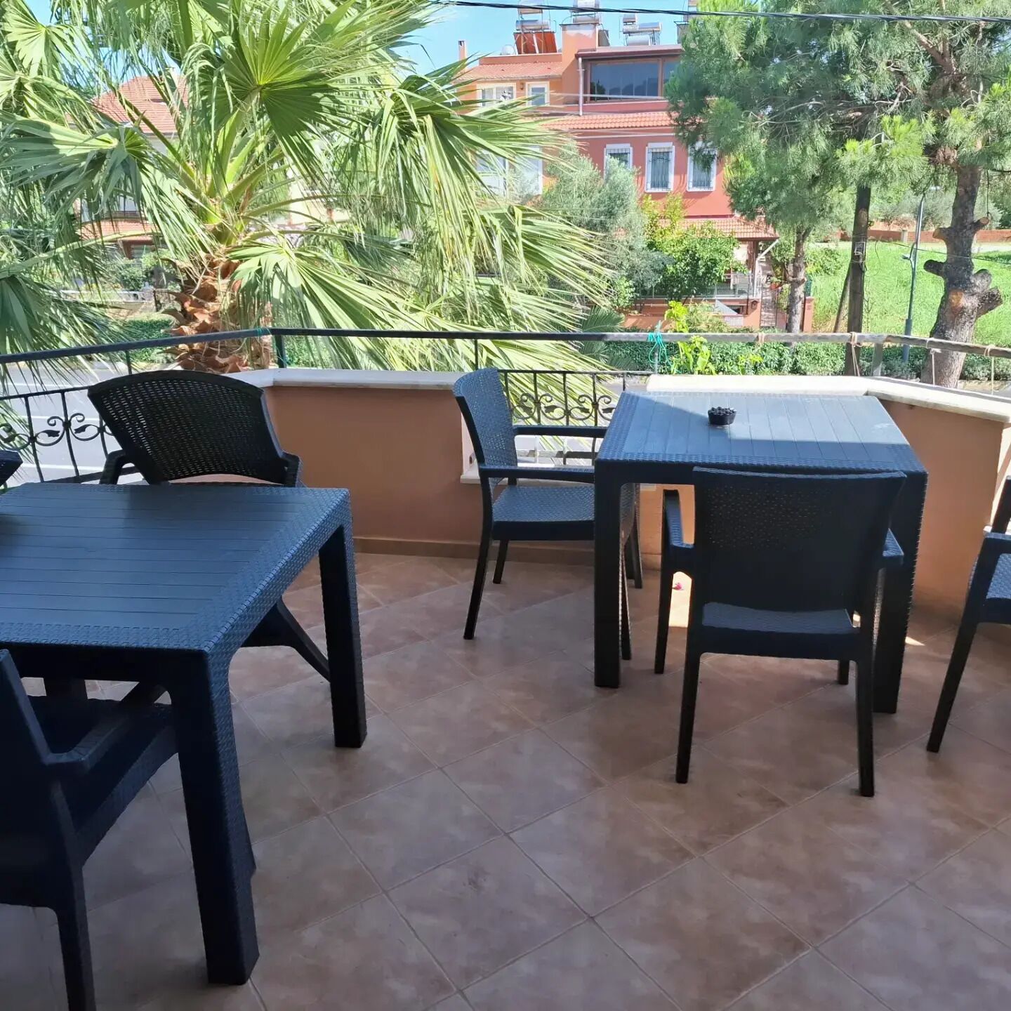 A balcony with outdoor furniture, a palm tree, and a view of buildings.