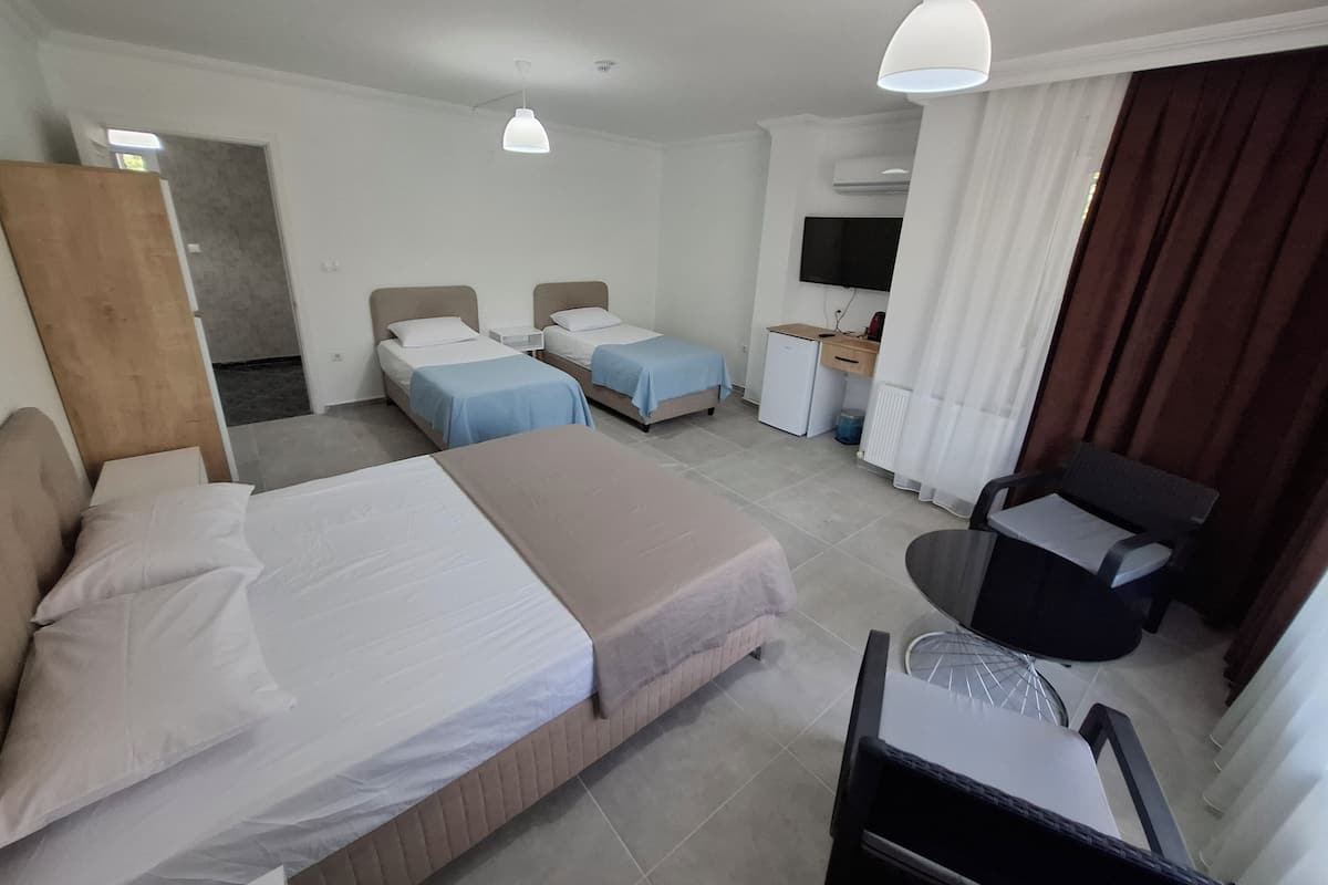 A hotel room with two single beds, a desk with a chair, a television, and a wardrobe.
