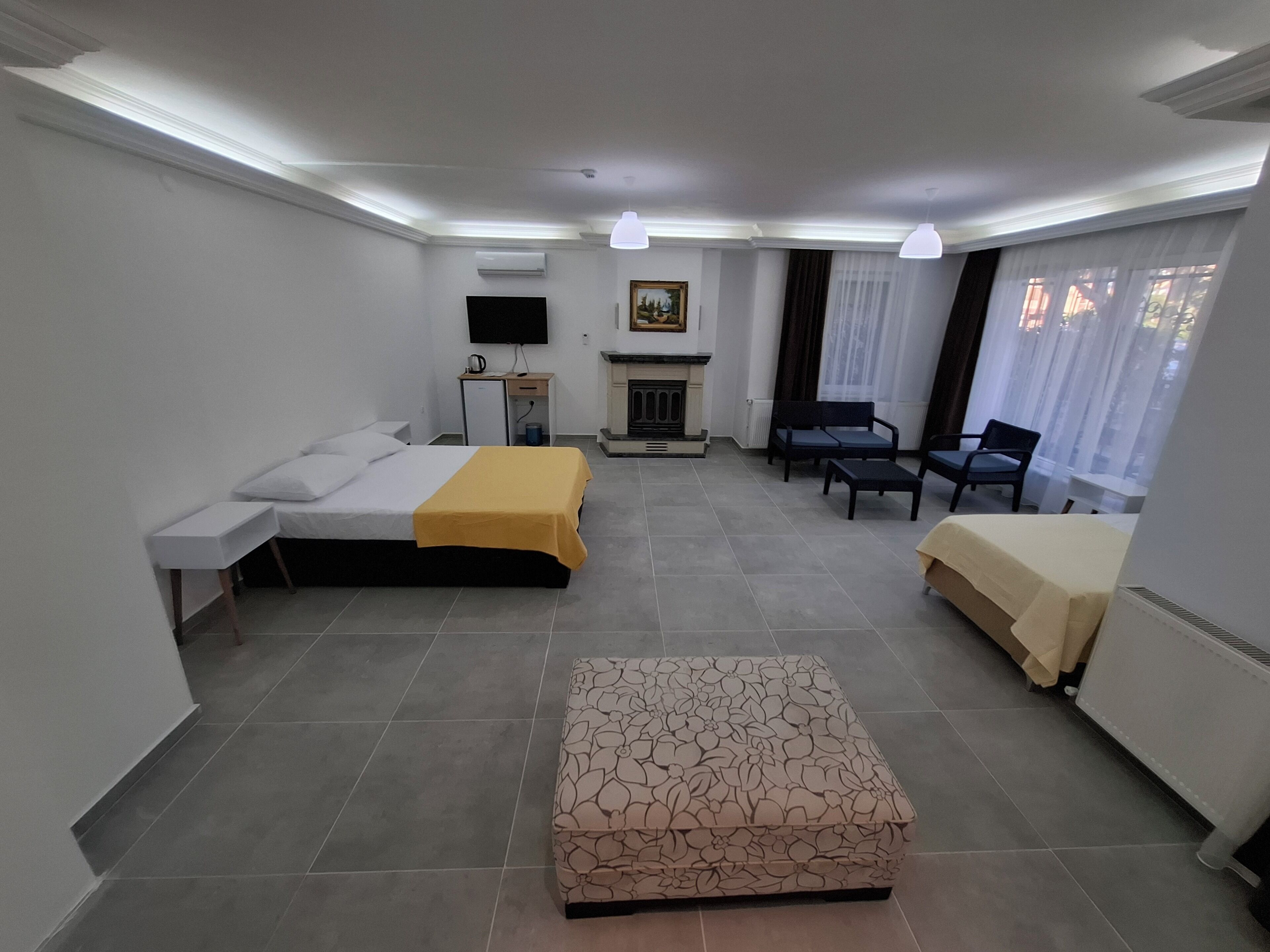 Una habitación de hotel con dos camas, un sofá, una pequeña mesa, una chimenea y un televisor.