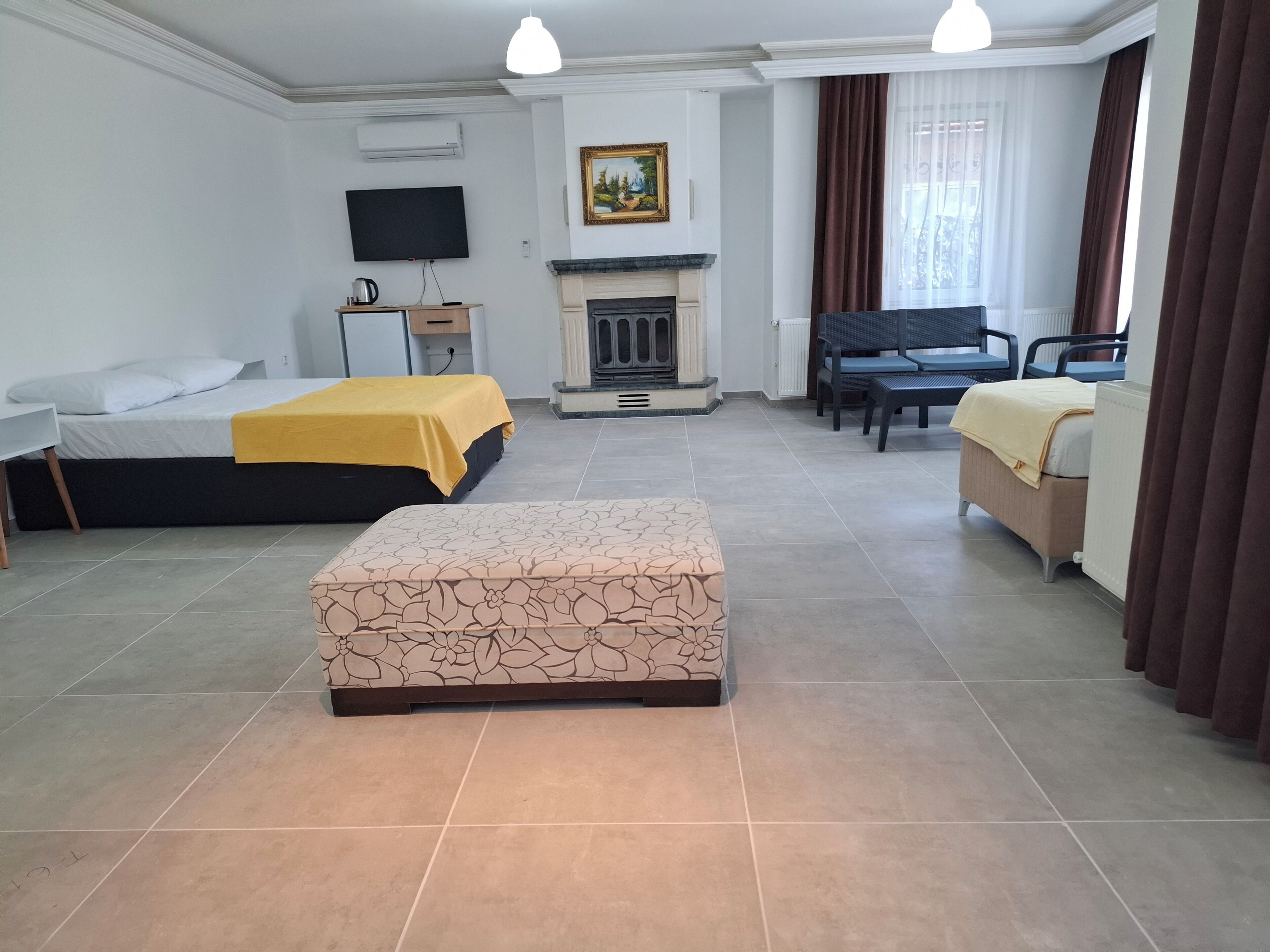 Habitación de hotel con dos camas, un sofá, una chimenea, un televisor y vistas al exterior.