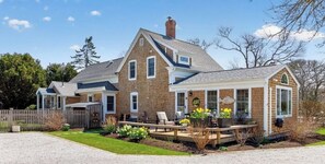Ein zweigeschossiges Haus mit überdachter Terrasse, umzäunter Garten und Kiesweg.