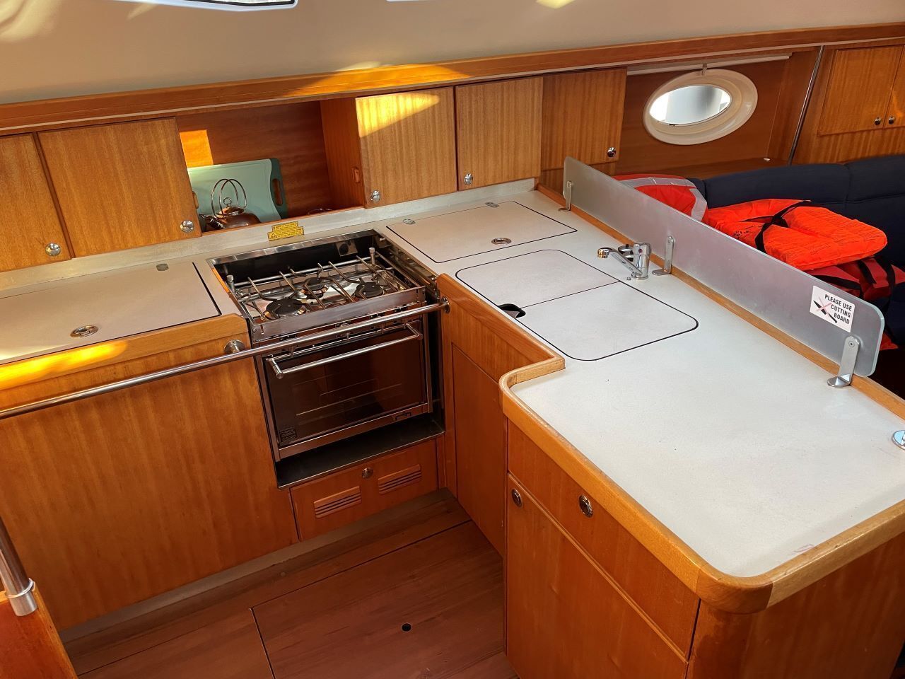 A compact kitchen with wooden cabinets, a stove, and a sink.