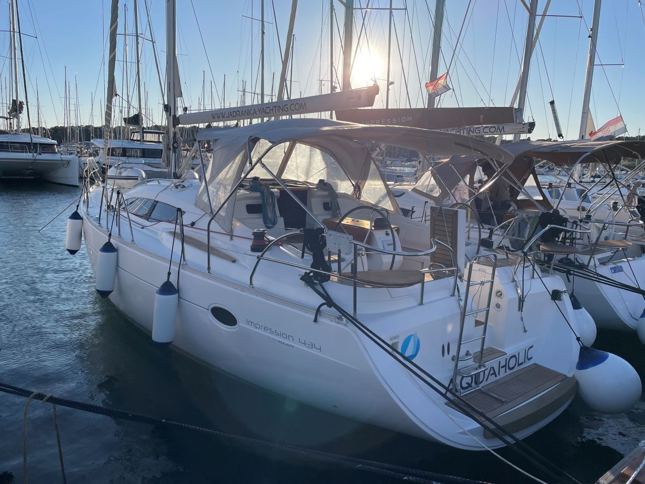 Un yacht blanc, baptisé « Impression 434 », était amarré dans une marina, aux côtés d’autres yachts. On pouvait y voir une bannière de site web avec l’adresse « WWW.JADRANKYACHTING.COM » et un logo représentant « QUAHOLIC ».