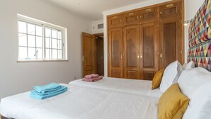 A bedroom with a large bed, wooden wardrobe, and a window. - FU1 in Moncarapacho With 6 Bedrooms and 6 Bathrooms (Olhao)